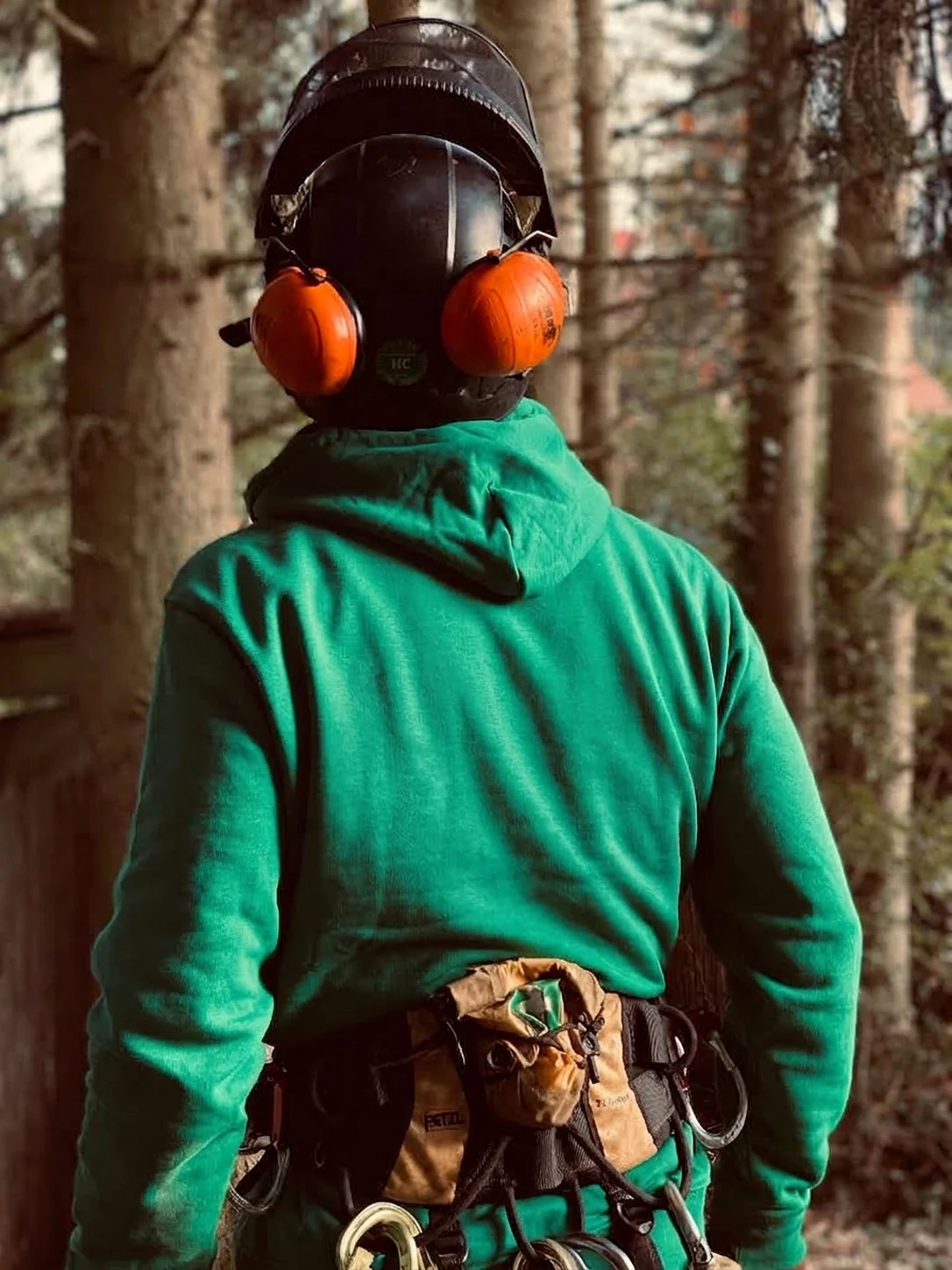 Grimpeur de dos, casque et baudrier, prêt à monter.